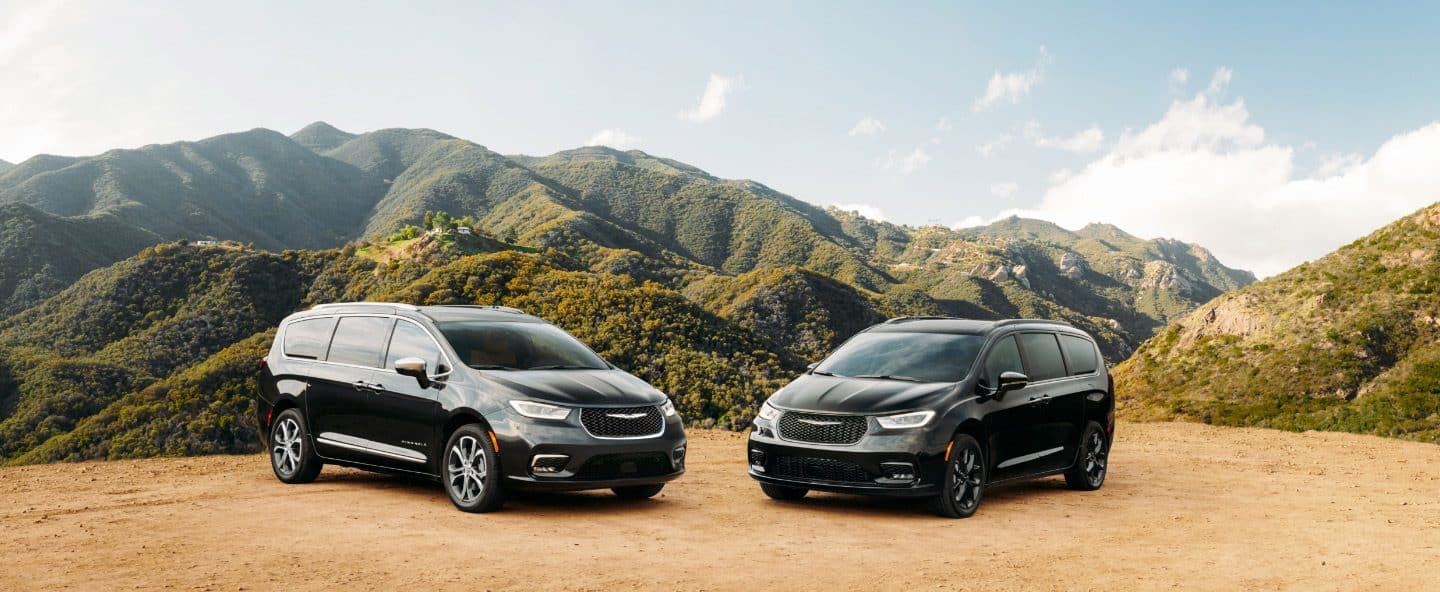 Dos modelos Chrysler Pacifica 2023 estacionados en un claro en las montañas. A la izquierda, una Chrysler Pacifica Pinnacle 2023 y, a la derecha, una Chrysler Pacifica Limited 2023 con el paquete de apariencia S.