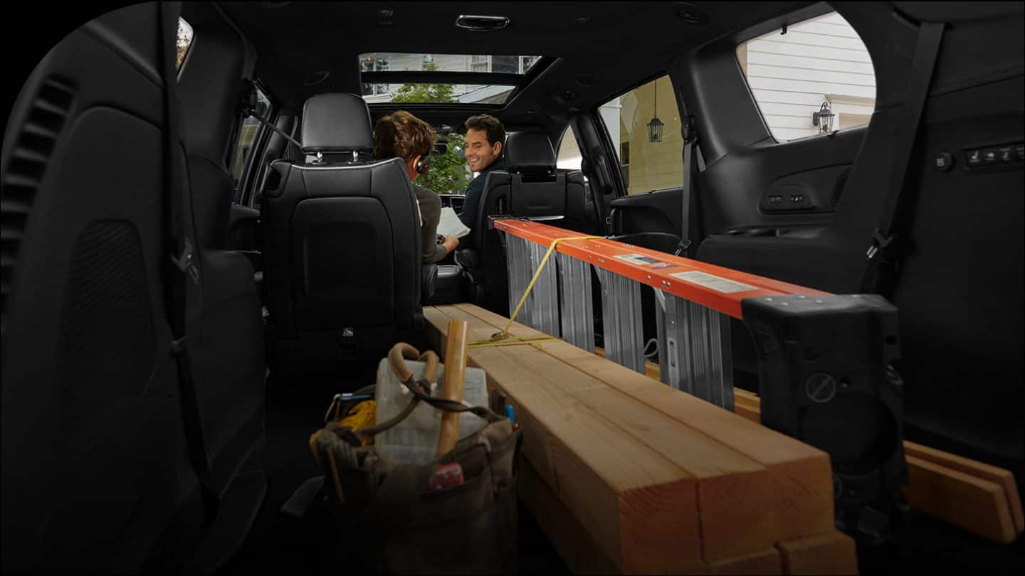 The interior of the 2026 Chrysler Pacifica with the third-row and one of the second-row Stow n Go seats folded into the floor, in order to accommodate a ladder and long pieces of lumber.