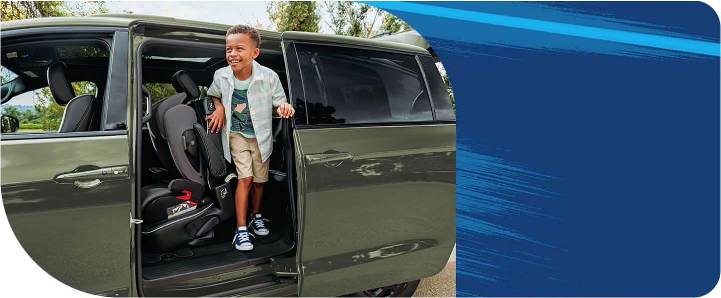 The second-row seat tilted forward with a rear-facing infant seat attched, as a child exits the third row through the driver-side siding door of a 2026 Chrysler Pacifica Plug-In Hybrid Select with the Premium S Appearance Package.