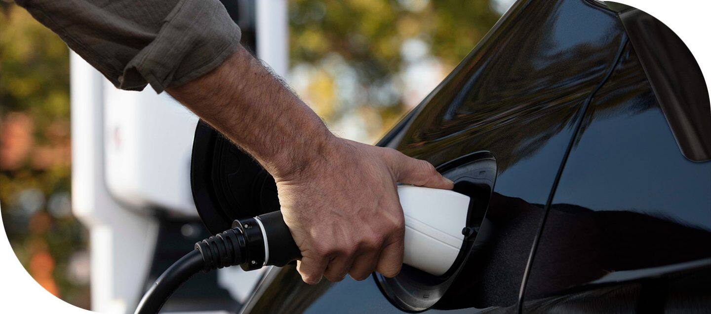 A man plugging a charging cord into the charging port of the 2026 Chrysler Pacifica Plug-in Hybrid.