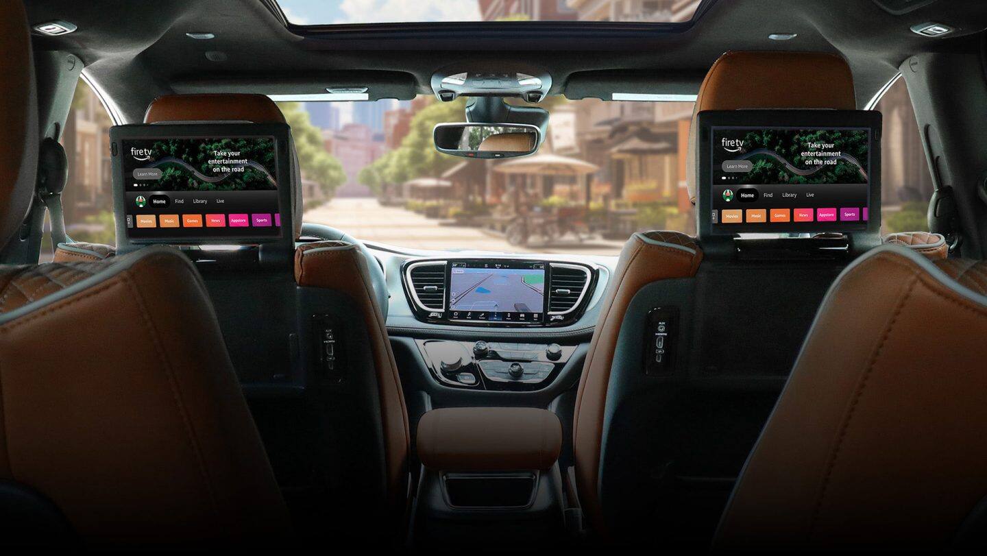 The interior of the 2026 Chrysler Pacifica Pinnacle from the third-row perspective forward, focusing on the dual front seatback-mounted touchscreens for second-row passengers, which are both displaying Amazon FireTV.