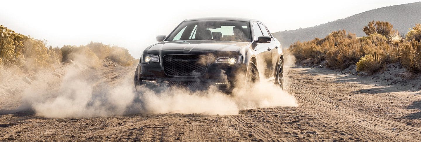 The 2021 Chrysler 300 Touring being driven on a sandy trail with a cloud of dust coming from its wheels.