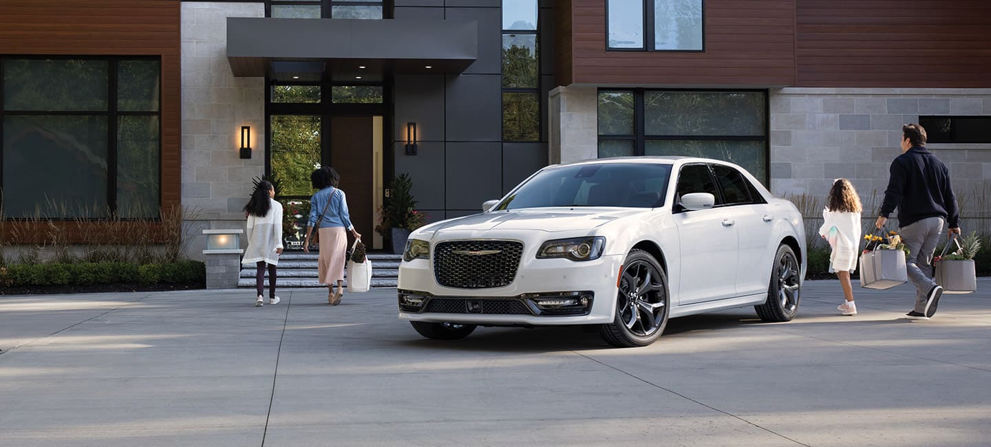 The 2021 Chrysler 300S V8 parked in front of a house with a family walking toward the front door.