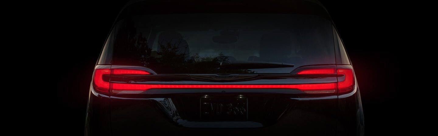 A rear view of the 2021 Chrysler Pacifica with its full-width LED taillamp lit.