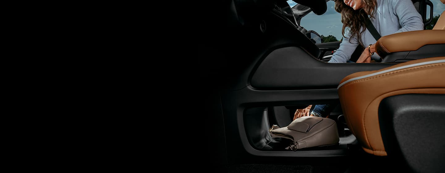 A passenger tucks her purse into the open area under the ultra console in the 2021 Chrysler Pacifica Pinnacle.