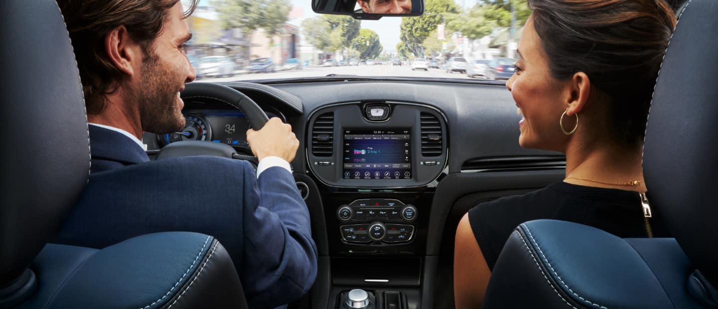 The interior of the 2023 Chrysler 300 with a driver and front passenger talking to each other in the front seats.