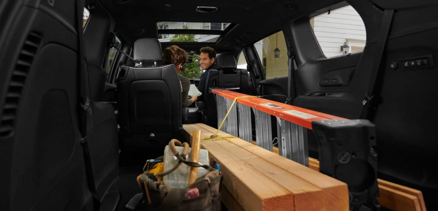 Display The interior of the 2023 Chrysler Pacifica Limited with the S Appearance Package, with the second- and third-row Stow n Go seats folded into the floor in order to accomodate a ladder and long pieces of lumber.