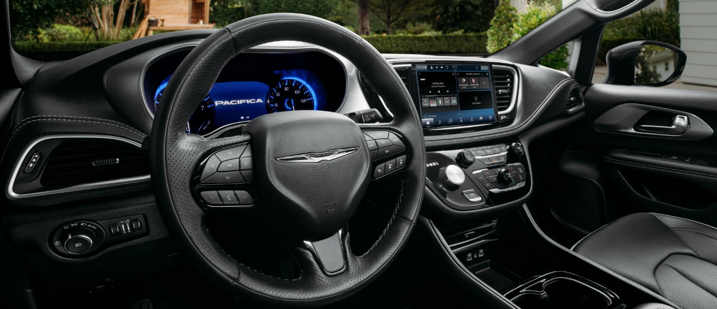 The interior of the 2023 Chrysler Pacifica TBD Hybrid focusing on the steering wheel, Digital Cluster Display and Uconnect touchscreen.