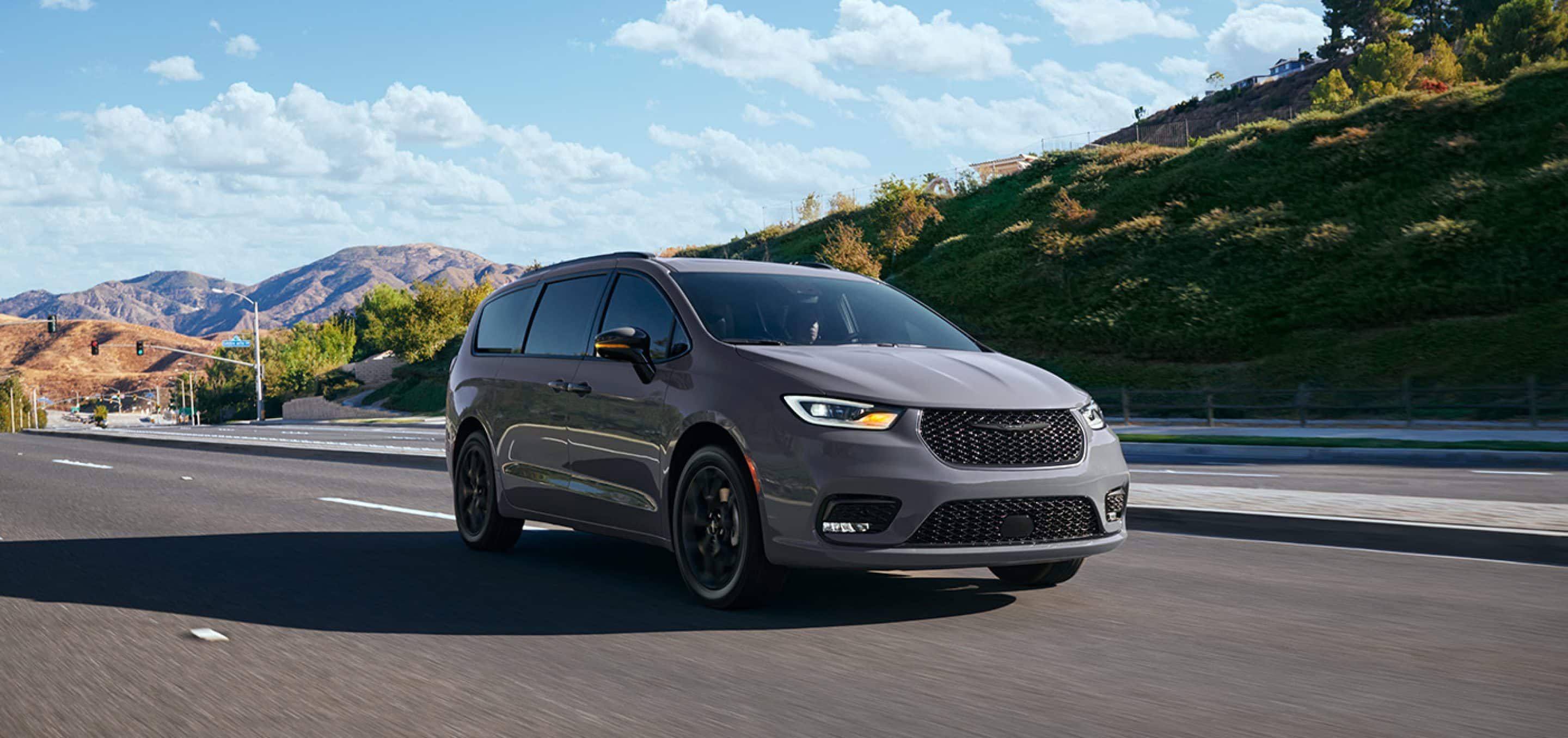 Chrysler Pacifica in Baltic-Gray driving on highway through mountain range. 