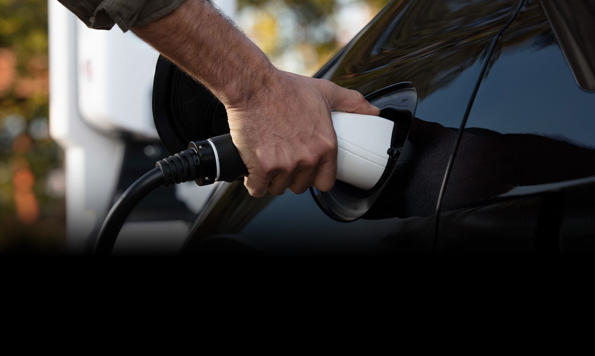 A man plugging a charging cord into the charging port of the 2025 Chrysler Pacifica Plug-in Hybrid.