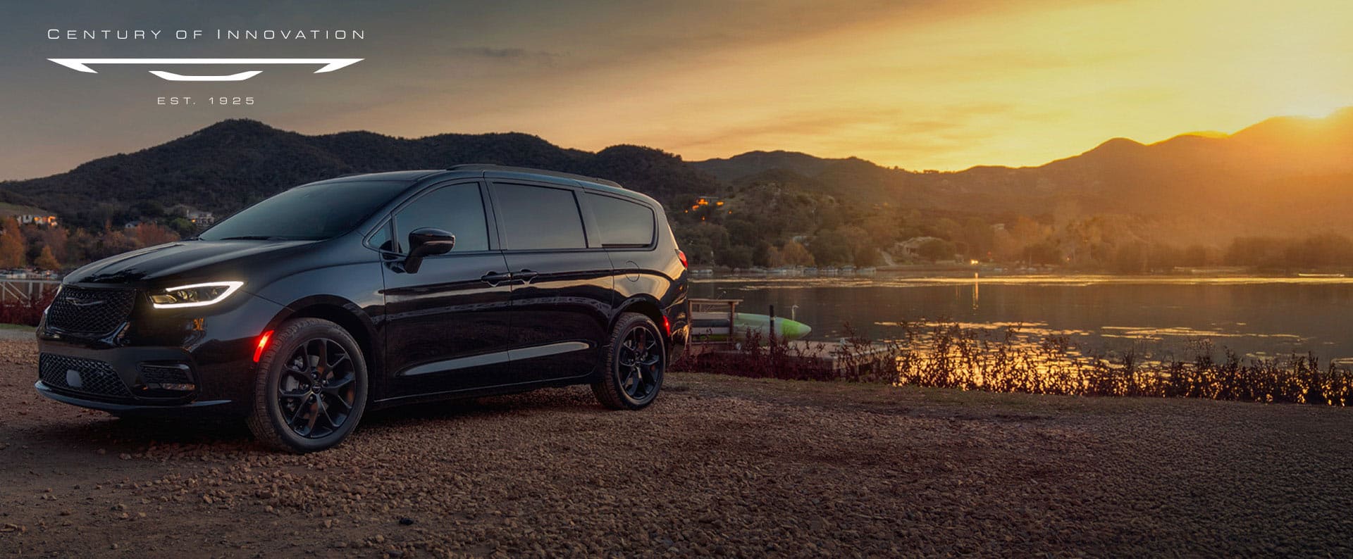 A black 2025 Chrysler Pacifica Limited parked by a lake at sunset. Employee Pricing Plus sales event. Century of Innovation.