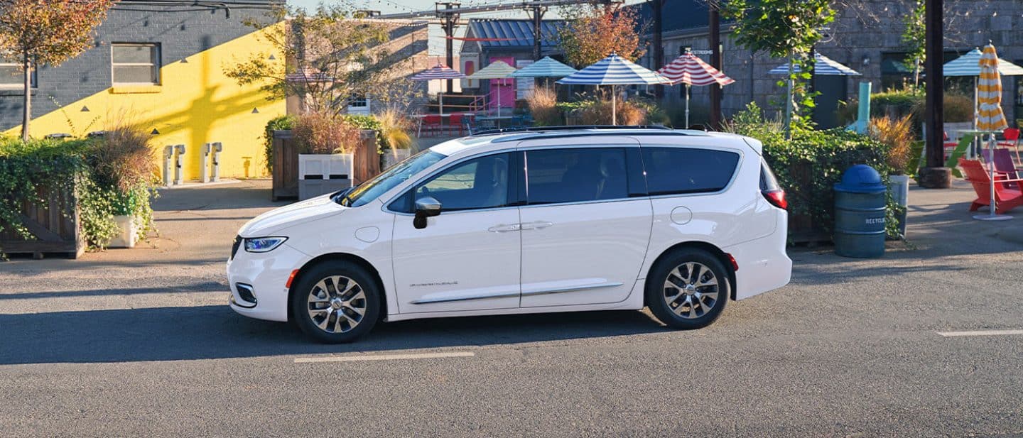 Display A driver-side profile of a white 2026 Chrysler Pacifica Plug-in Hybrid Pinnacle parked at tourist venue.