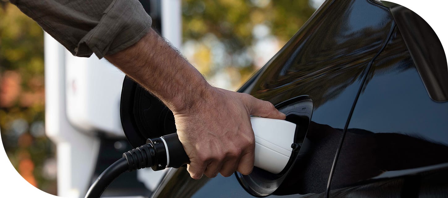 A man plugging a charging cord into the charging port of the 2026 Chrysler Pacifica Plug-in Hybrid.