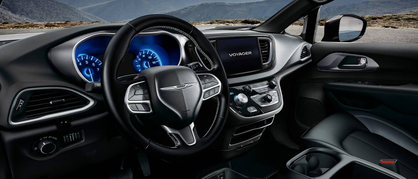 The steering wheel, Digital Cluster Display, Uconnect touchscreen and center stack controls in a 2026 Chrysler Voyager LX.