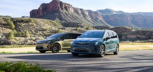 Two 2027 Chrysler Pacifica minivans parked opposite of each other--on the left an olive green Pacifica Limited with the S Appearance Package and a blue Pacifica Pinnacle on the right.