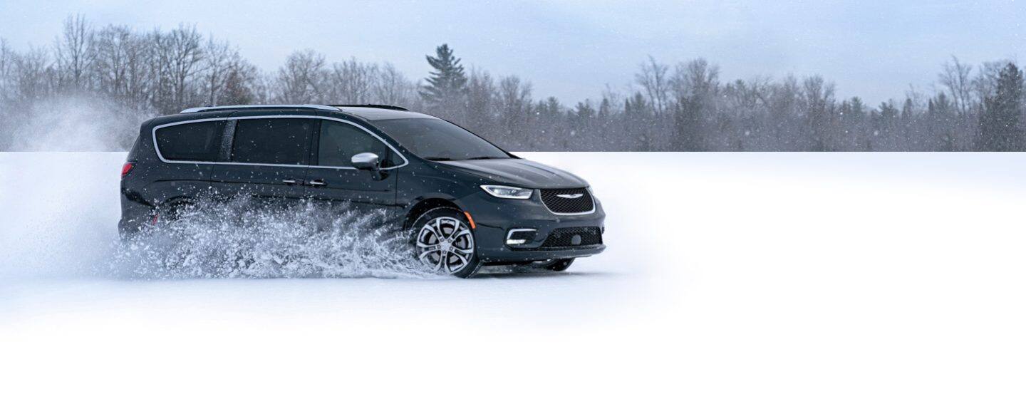 A 2021 Chrysler Pacifica Pinnacle being driven on loose snow, with a spray of snow coming from its wheels.