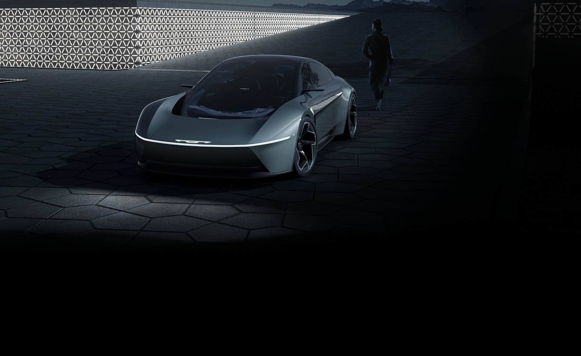 A raised front angle of a gray Chrysler Halcyon Concept vehicle parked in a darkened courtyard.