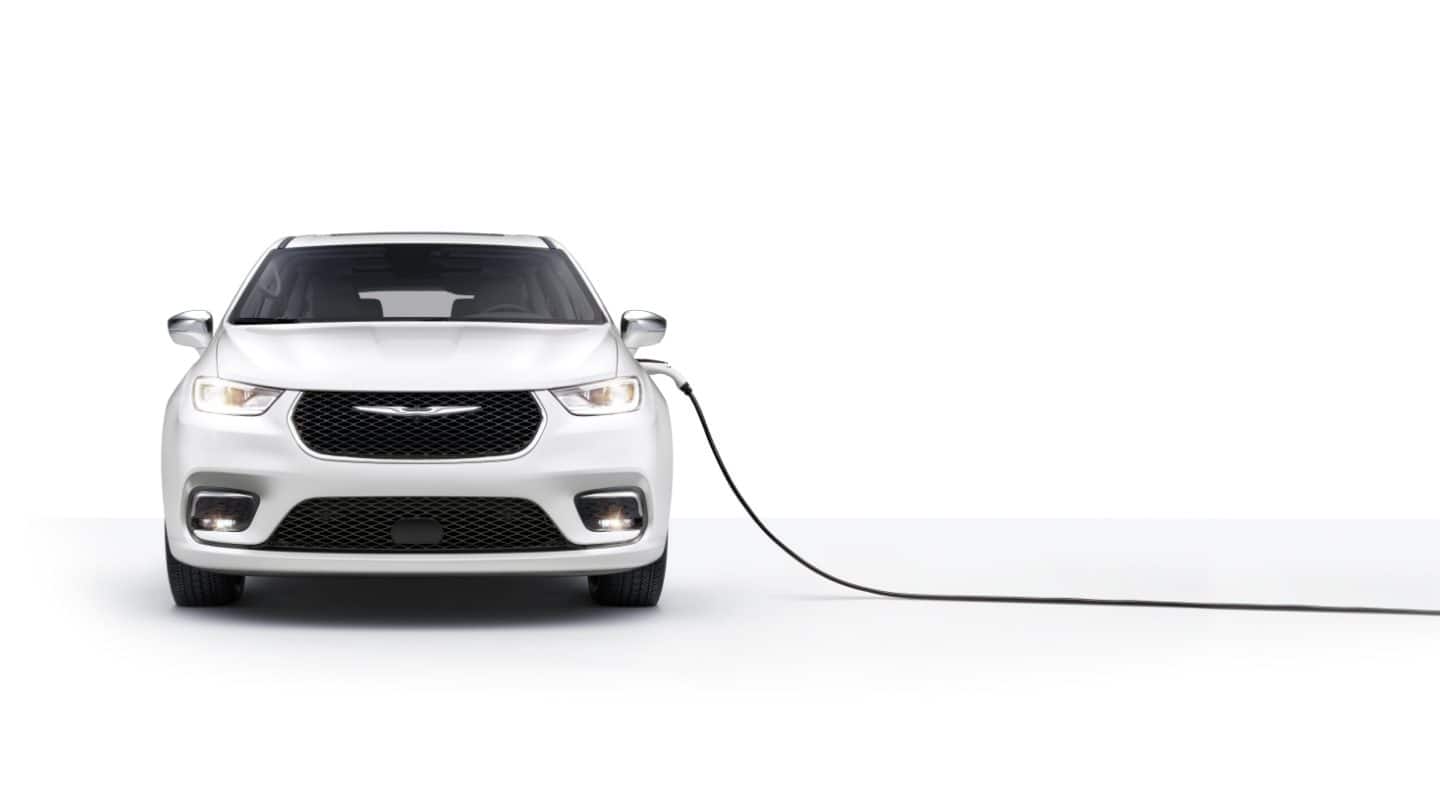 Head-on view of a Chrysler Pacifica Pinnacle Hybrid with a charger plugged into its charging port.