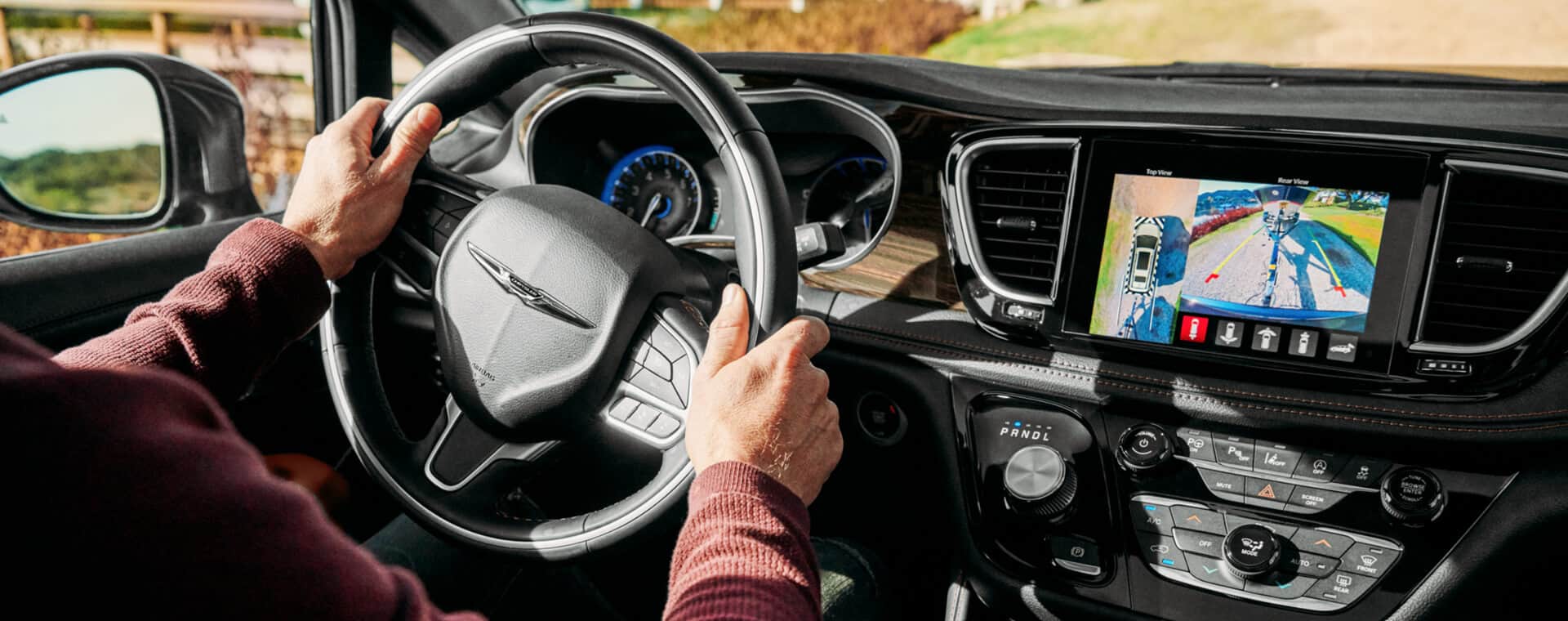 The driver of a 2021 Chrysler Brand vehicle watching the road while keeping his hands on the steering wheel.