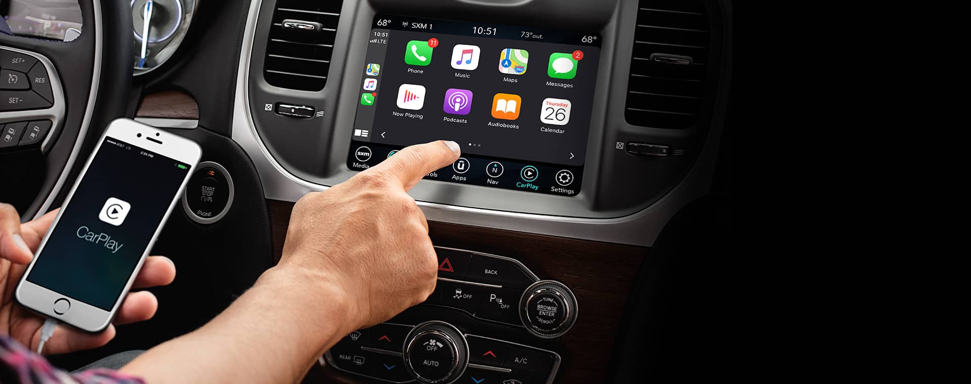 The driver in a 2021 Chrysler Pacifica Limited using the Uconnect touchscreen to access his smartphone's features.